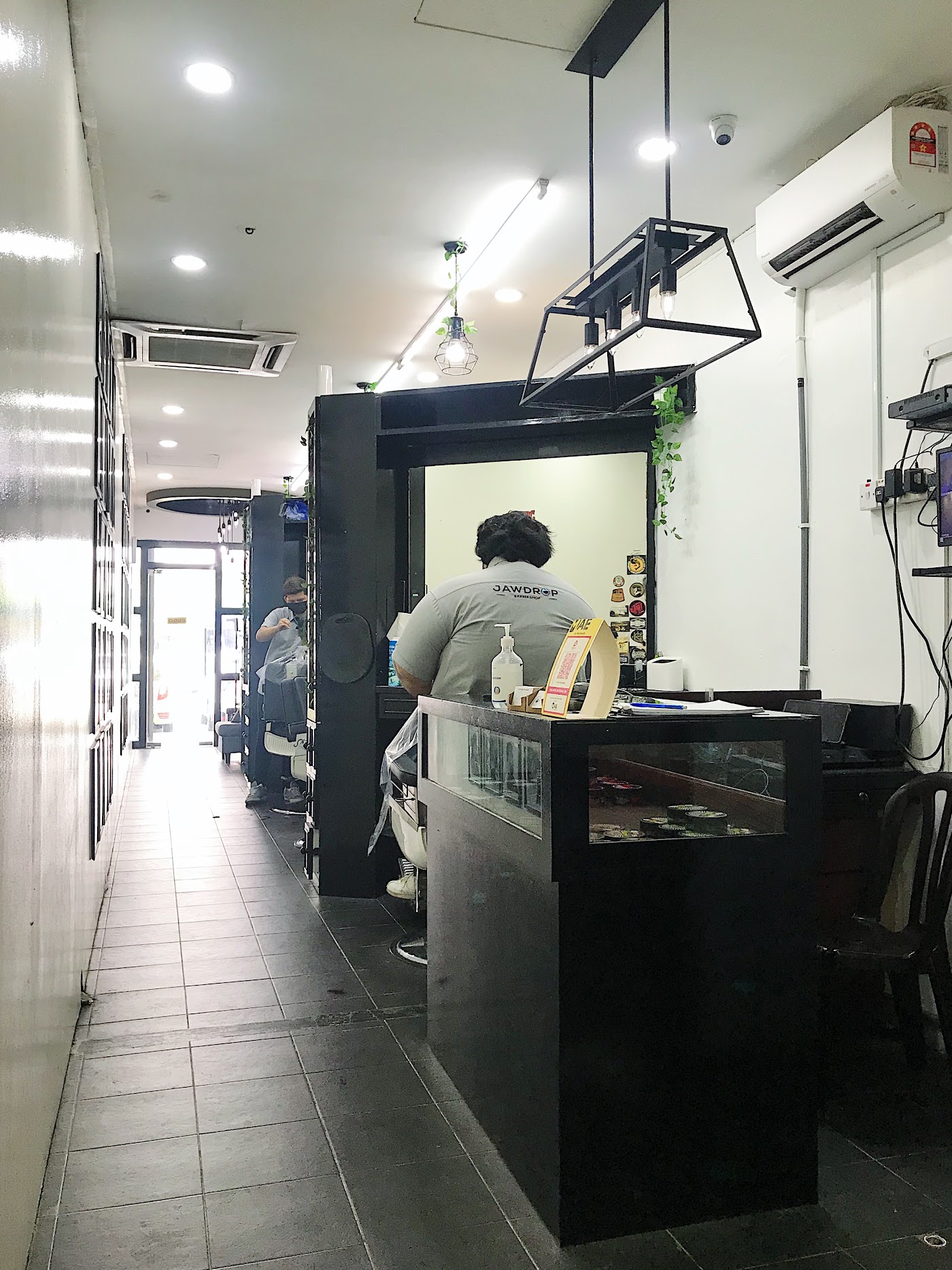 Jawdrop barber attending to a client near the front counter